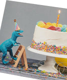 Greeting card for him or friend featuring a cake and dinosaur design, by UK Greetings, with colorful birthday illustrations.