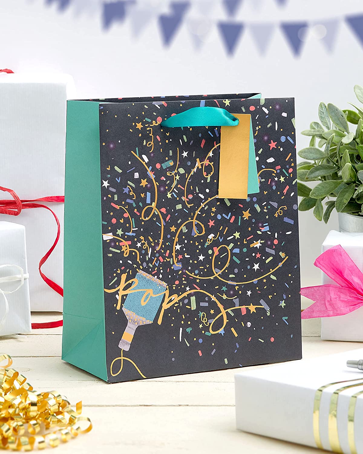 Medium UK Greetings party gift bag with attached tag, featuring colorful design and space for personalized message.