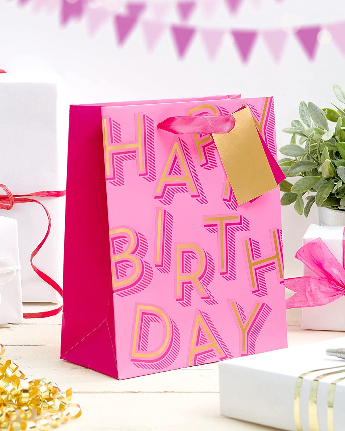 Medium pink UK Greetings gift bag with birthday lettering and decorative design, perfect for celebrating special occasions.