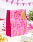 Medium pink UK Greetings gift bag with birthday lettering and decorative design, perfect for celebrating special occasions.