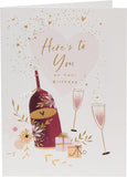 Birthday greeting card featuring wine bottles, glasses, and presents with UK Greetings branding.