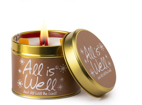Lily-Flame All is Well scented tin candle with a decorative label and metal lid, emitting a warm, inviting glow.