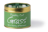 Lily-Flame Freshly Cut Grass scented tin candle with a green label, featuring a natural, relaxing outdoor grass scene.