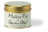 Lily-Flame Mellow Figs and Garden Mint scented tin candle with a decorative label and a lit wick, emitting a warm glow.