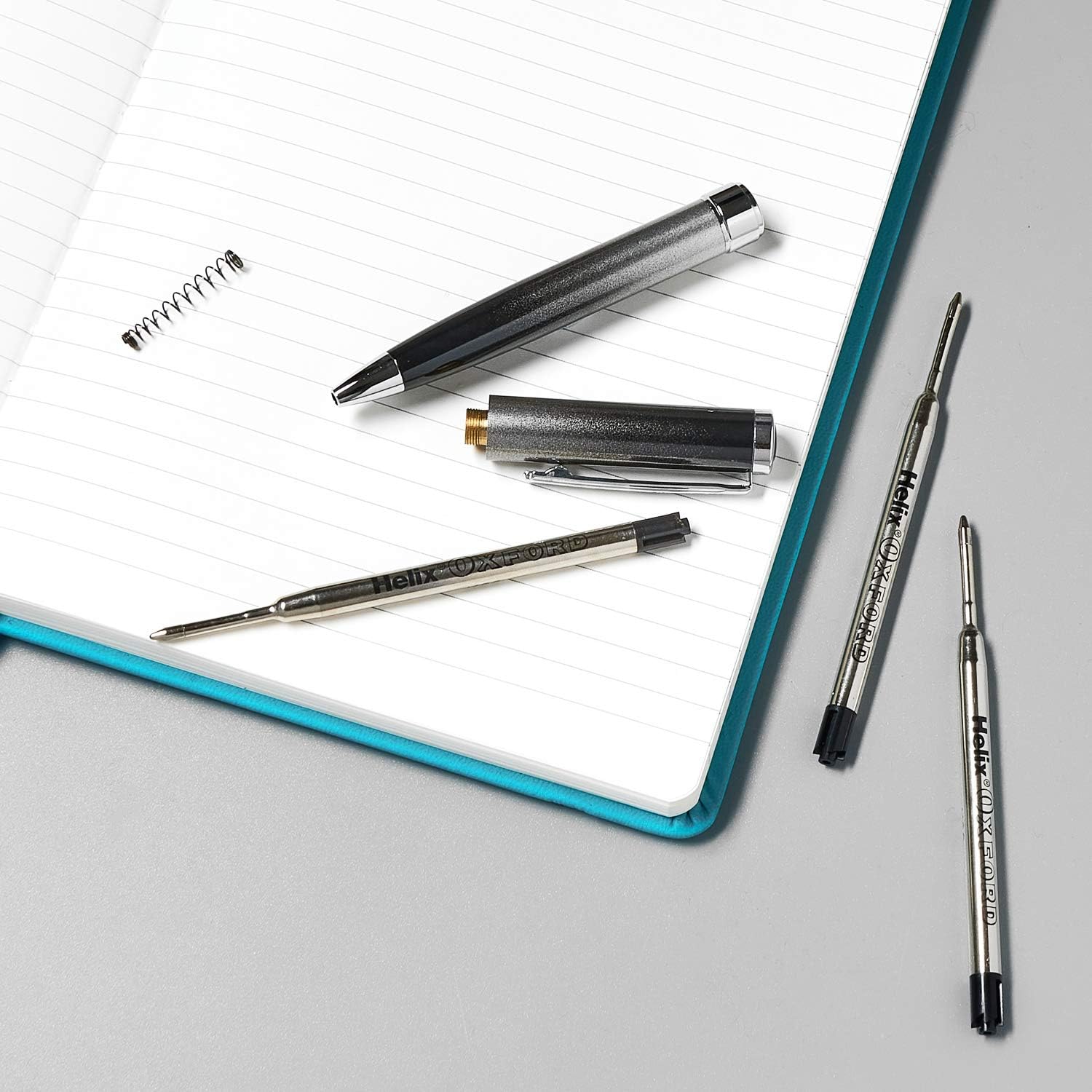 Two Oxford Helix Oxford ballpoint pen refills with black ink, showing the pen tips and packaging.