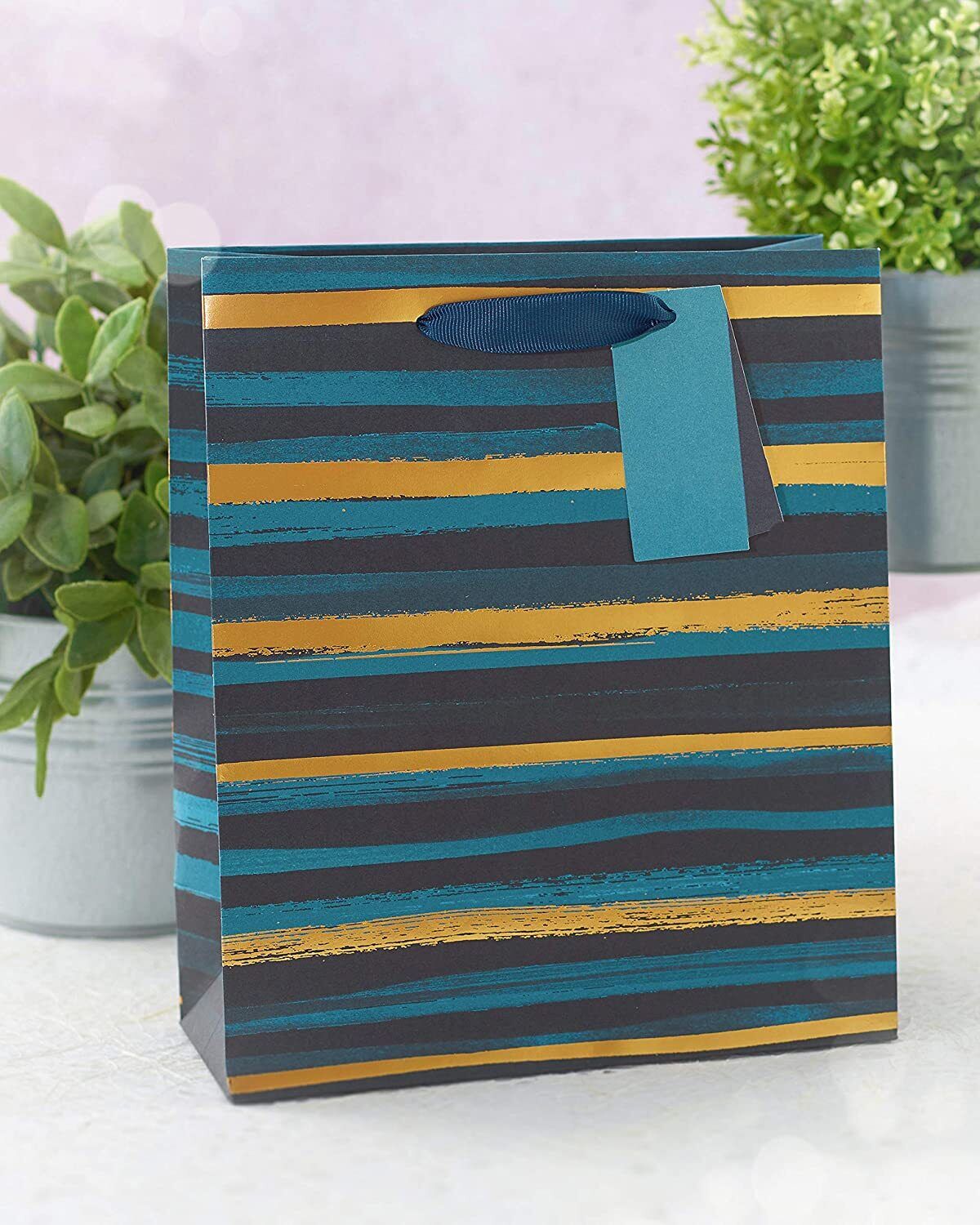 Elegant blue and gold striped gift bag with greeting card design by UK Greetings, featuring a stylish and festive appearance.