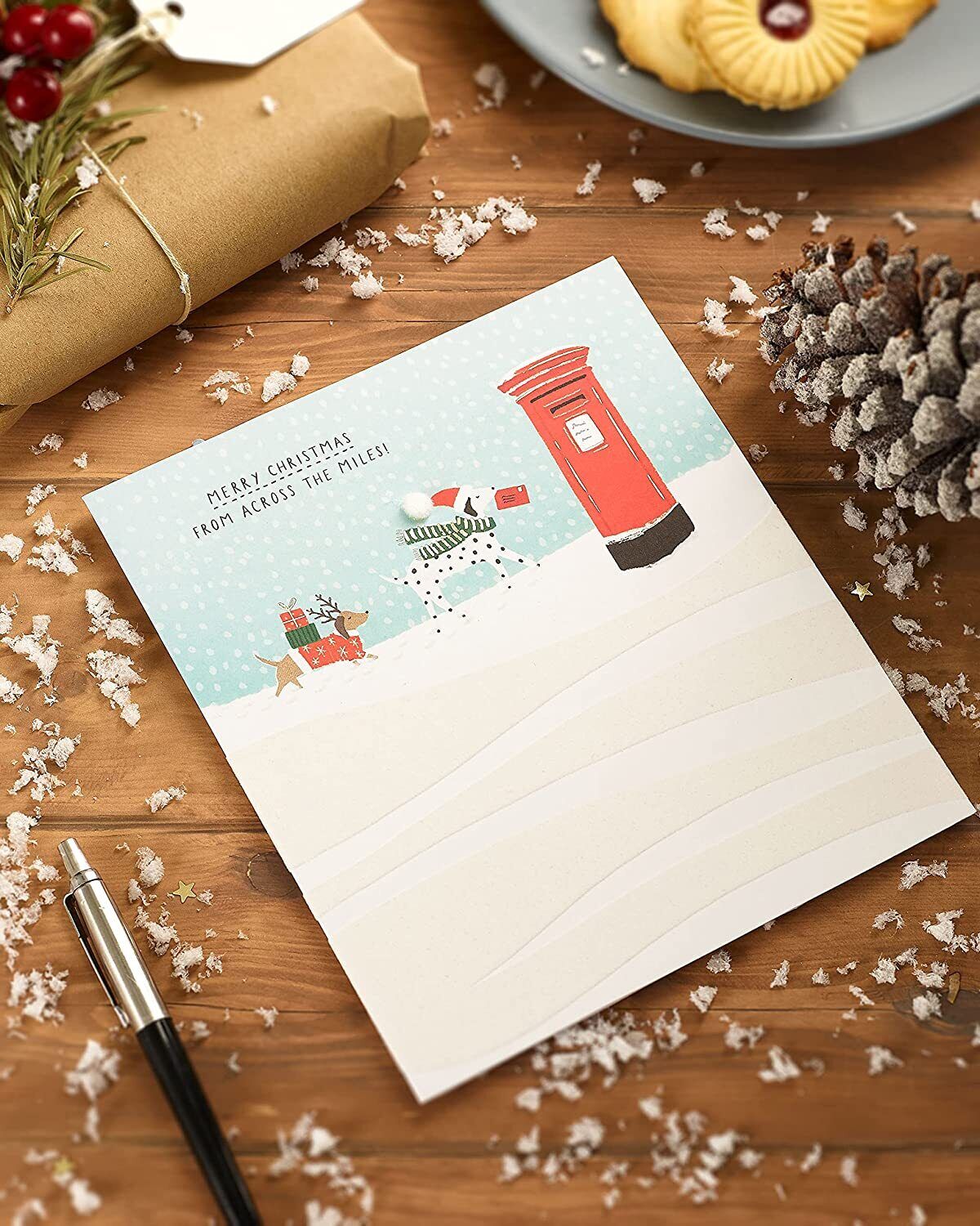 Festive Christmas greeting card featuring snow dogs across the miles design by UK Greetings, decorated with holiday motifs.