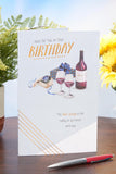 Birthday greeting card featuring a watch and wine design, UK Greetings brand, with colorful illustrations on the front.